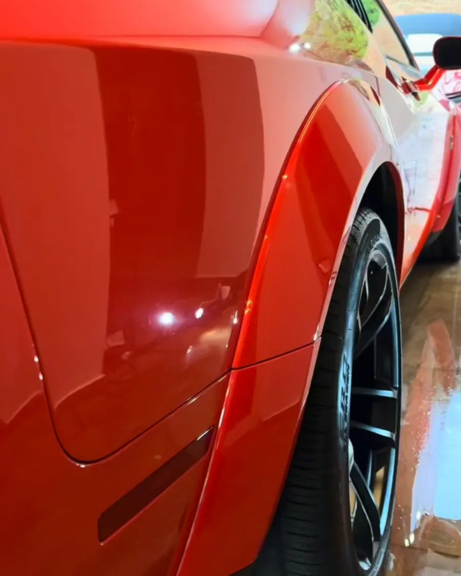 Lateral traseira de um esportivo vermelho com reflexo espelhado depois do polimento